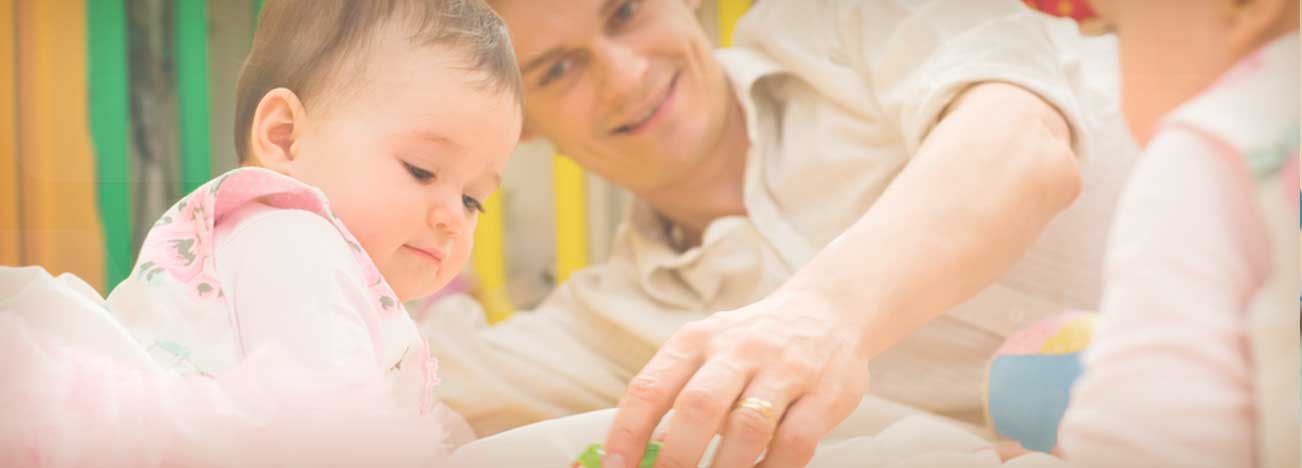 Papá acostado y jugando mientras ve a uno de sus dos bebés.