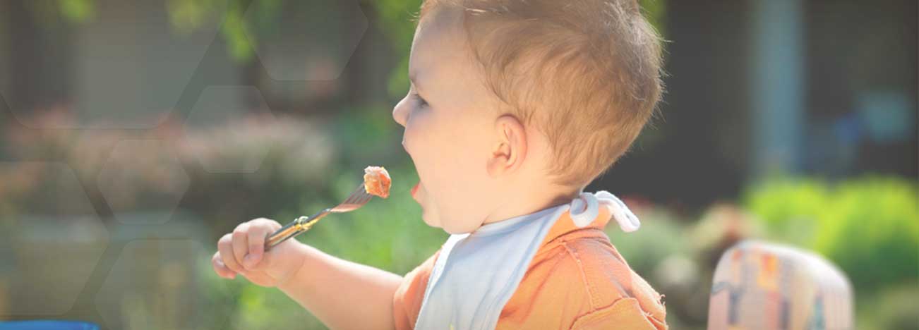 Niño llevando una cuchara de comida a su boca.