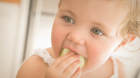 Niña sosteniendo fruta con su mano.