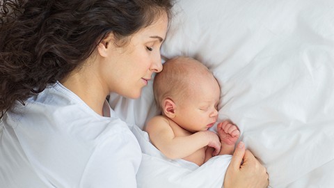 Mamá durmiendo con bebé recién nacido